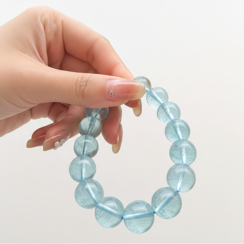 Hand holding a blue beaded bracelet against a white background